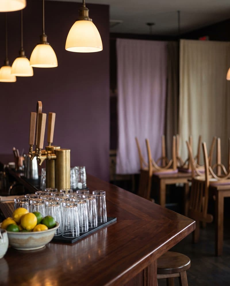 Clean glasses and brass taps on a wooden bar before the restaurant opens